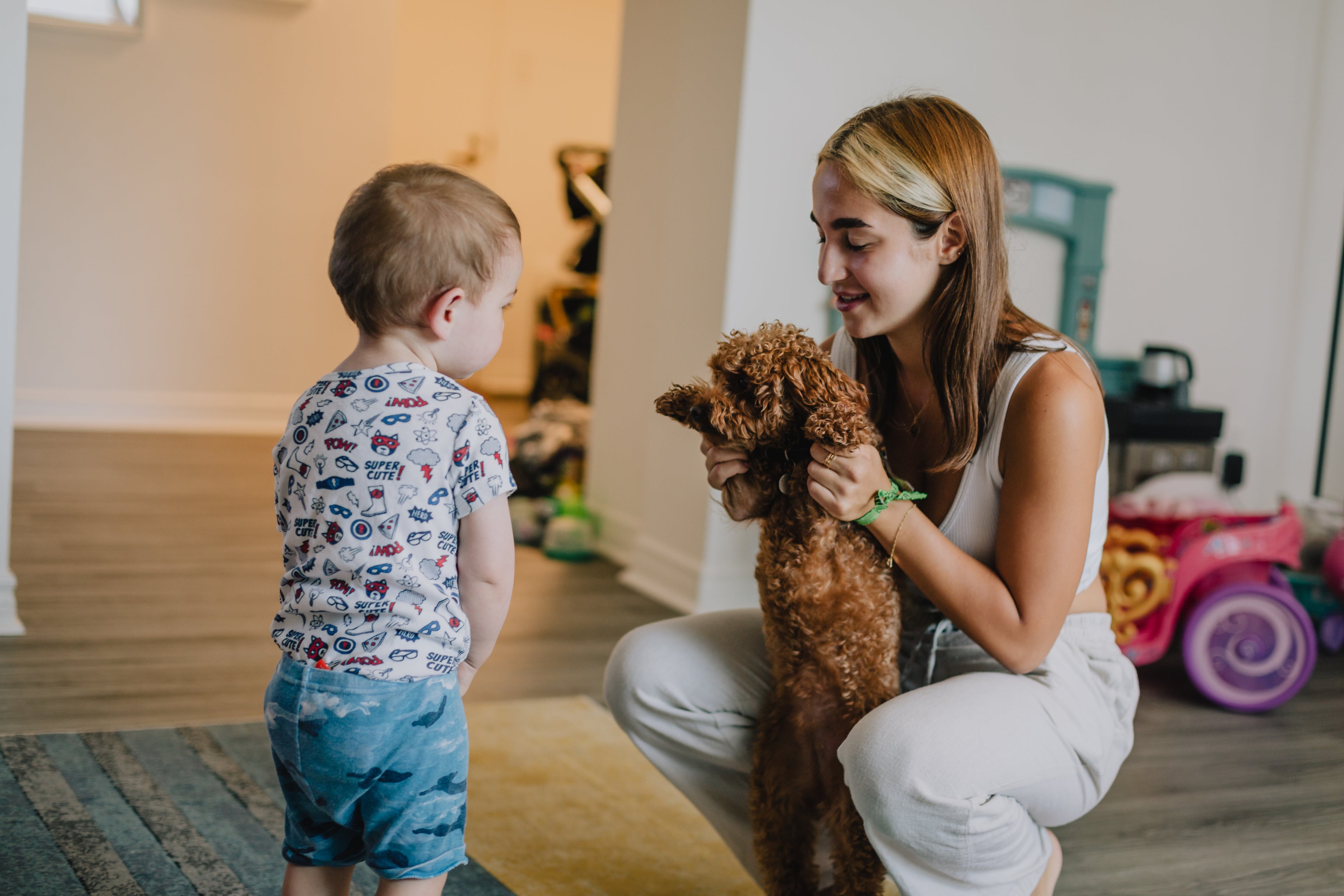 Kind begroet puppy die wordt vastgehouden door volwassene, gezin met hond